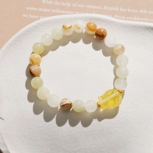 Detail of beaded bracelet featuring semi-transparent agate beads and a yellow fish charm