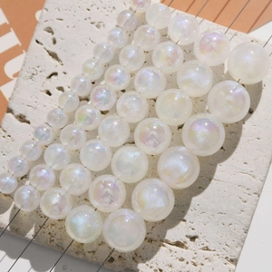Macro shot of iridescent pearlescent acrylic beads in five sizes on a travertine stone