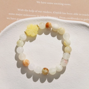 Detail of beaded bracelet with colorful natural stones and a yellow clover charm pendant
