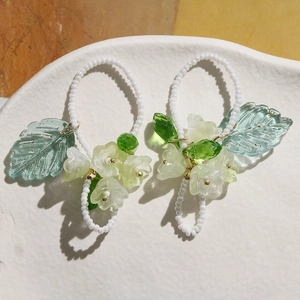 Boucles d'oreilles artisanales en perles avec fleurs et feuilles sur plat en céramique