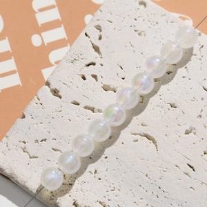 Detail of 6-8mm iridescent white acrylic beads with AB coating on travertine stone