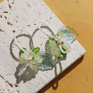 Détail de boucles d'oreilles en perles faites main avec fleurs en résine vert mat