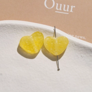 Close-up of a yellow heart resin bead with citrus pulp texture on a metal pin