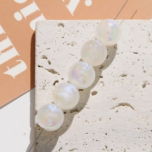 Close-up of iridescent mermaid pearl beads on a stone surface for DIY jewelry