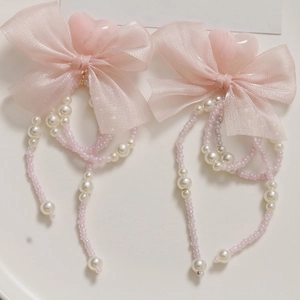 Detail of pink organza bow charms with dangling pearl tassels and heart bead accents