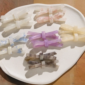 Détail de pinces à cheveux noeud en acétate en six coloris pastel sur plateau blanc