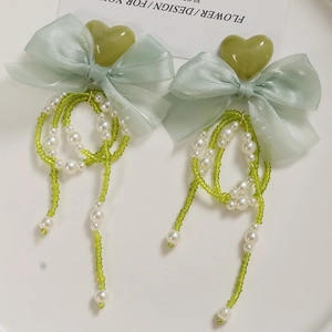 Detail of green heart charms with organza bows and long pearl tassel bead chains