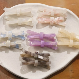 Détails de barrettes noeud en acétate de luxe en six couleurs sur plateau céramique