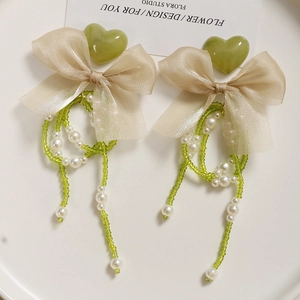 Detail of fairy-style long pearl chain with green heart and bow for shoe decoration