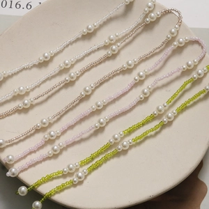 Detail of long pearl chain accessory with pink and green beads for DIY crafting and clogs