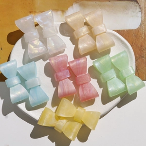 Detail of colorful bow-shaped hair clips in white, pink, blue and green resin pearls
