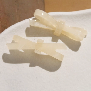 Vue détaillée de deux barrettes noeuds en acétate blanc crème avec texture marbrée
