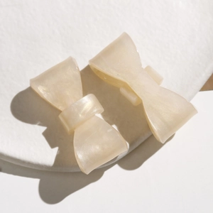 Macro detail of creamy AB iridescent bow hair clips with pearlescent acetate texture