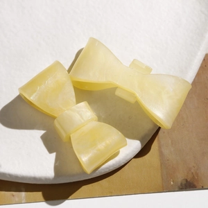 Detail of yellow acetate bow hair clips with marble texture on a stone tray