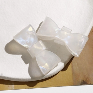 Close-up of iridescent pearly bow hair clips with a subtle shimmering finish on a plate