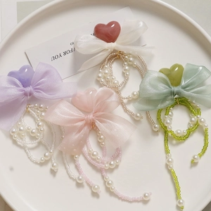 Detailed view of DIY pearl chain accessories with bows and hearts in pastel colors