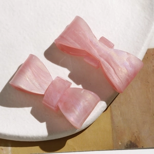 Close-up of dual pink iridescent acetate bow hair clips on a white frosted tray