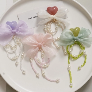 Detail of long pearl chain hair clips with macaron organza bows in pastel colors