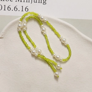 Close-up of long green bead and white pearl chain accessories for DIY shoes and crafts