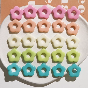 Flat lay of colorful resin five-petal flower beads for DIY jewelry making in ceramic tray