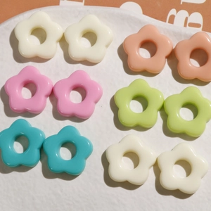 Macro view of colorful resin five-petal flower charms in a white ceramic dish