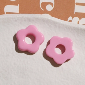 Pink resin five-petal flower charms for DIY jewelry making on white ceramic plate