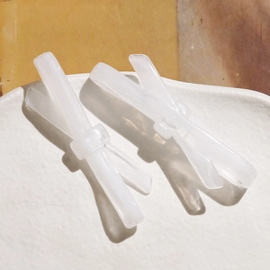 Détail de barrettes nœuds en acétate blanc crème avec une texture brillante élégante