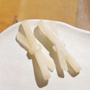 Détail de barrettes à cheveux en résine marbrée crème sur un plateau de présentation