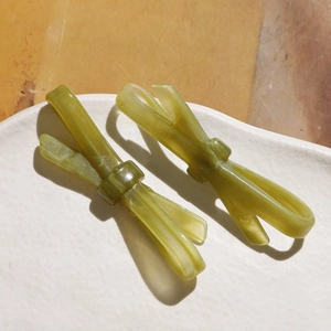 Détail de barrettes noeuds en résine verte avec texture marbrée sur assiette blanche
