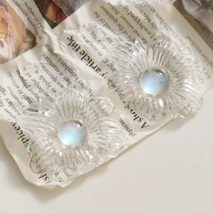 Macro shot of transparent acrylic daisy charms with iridescent opal center on vintage paper