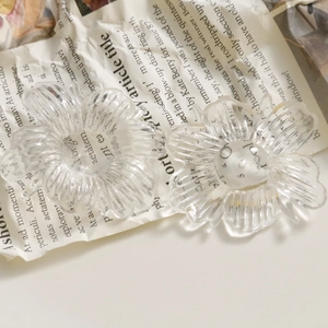 Macro detail of transparent acrylic flower charms with multi-petal 3D design on paper