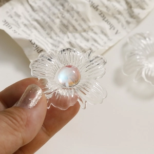 Macro detail of transparent acrylic flower with striped petals and iridescent pearl core