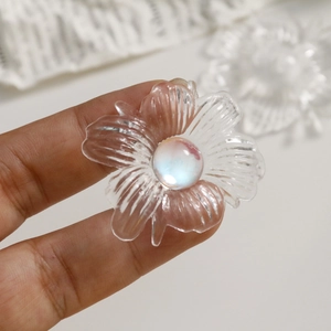 Close-up of clear acrylic flower charm with iridescent pearl center for DIY crafts