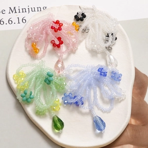 Detailed close-up of beaded floral tassel charms in pink, white, mint green, and blue hues