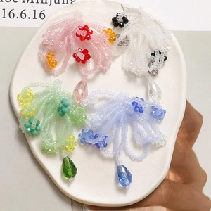 Detail of colorful beaded flower pendants with crystal teardrop charms on a ceramic tray