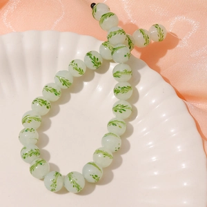 Detail of 13mm light green glass beads with plant patterns for DIY jewelry making