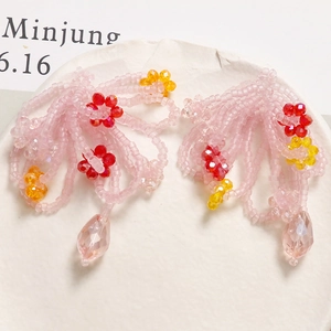 Detail of pink handmade beaded flower earrings with crystal drop charms and frosted beads