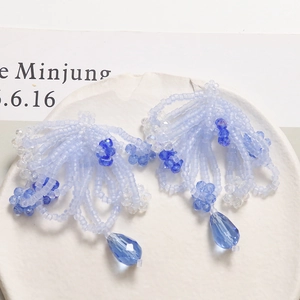 Detail of beaded tassel earrings featuring blue crystal flowers and teardrop pendant