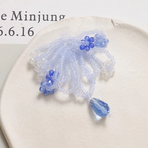 Detailed view of handmade blue beaded bow hair clip with crystal flower and teardrop charm