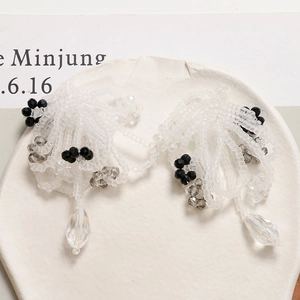 Detail of handcrafted beaded tassel earrings with crystal drops on a stone tray