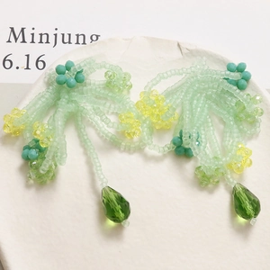Detail of beaded tassel earrings with green crystal water drops and yellow flowers