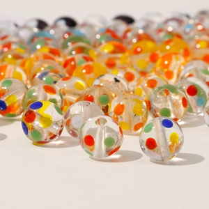 Macro shot of 12mm clear glass beads with colorful polka dots and center drill holes