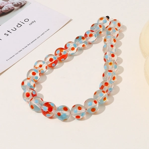 Detailed macro view of 12mm glass beads with orange and blue dots for DIY jewelry