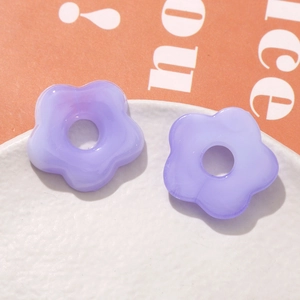 Close-up of lavender translucent 5-petal flower charms on white tray for DIY jewelry making