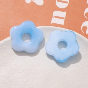 Macro view of light blue resin flower beads with subtle marble texture for DIY jewelry