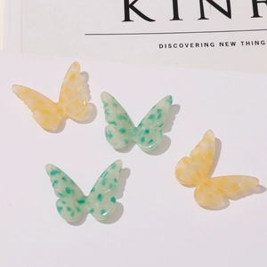 Close-up of butterfly acetate resin charms in mint green and amber with leopard spots