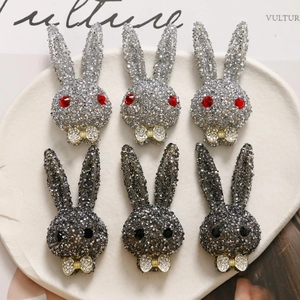 Detailed view of rhinestone rabbit charms in silver and grey with golden bowties