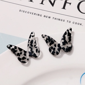 Detail of butterfly-shaped acetate earrings with black and white spotted leopard texture