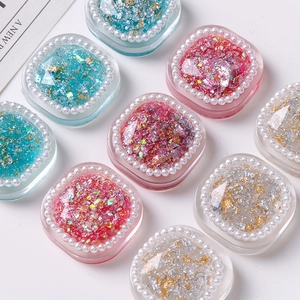 Macro view of square resin charms with gold foil, glitter, and white pearl trim detail