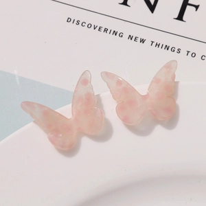 Close-up of pink translucent butterfly resin charms with subtle glitter and polka dots